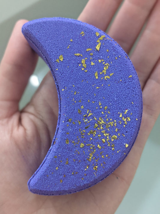 A purple moon shaped bath bomb with gold sparkles
